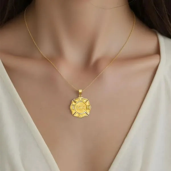 Firefighter badge pendant worn by woman in yellow gold