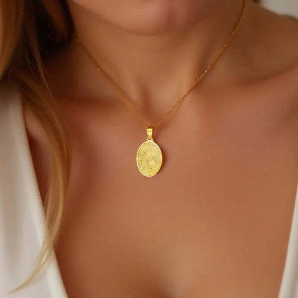 Oval fingerprint charm pendant worn in yellow gold