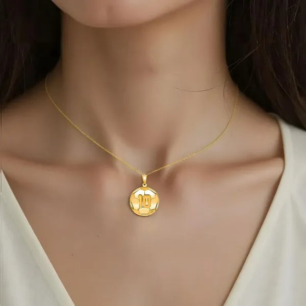 Soccer ball pendant worn by woman in yellow gold